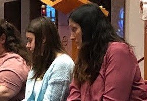 Judith Giger (right) and Karolina (second from right), a foreign exchange student she is hosting in her home this year, who also served as her godmother through the Rite of Christian Initiation of Adults, await having their feet washed during the Mass of the Lord’s Supper on Holy Thursday, April 14, in Our Lady of Lourdes Church in Columbia.